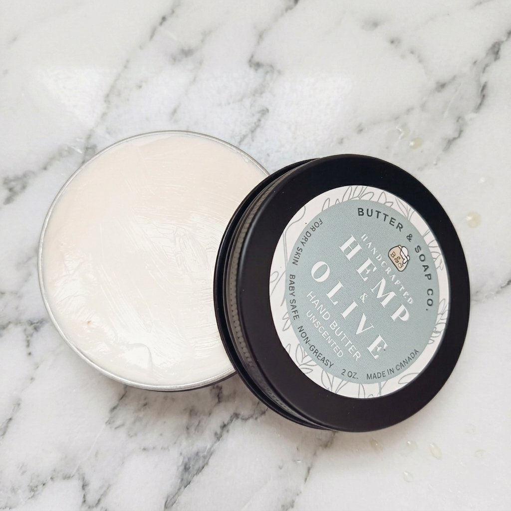 open tin of Butter & Soap Co. Hemp & Olive hand butter showing creamy texture on marble